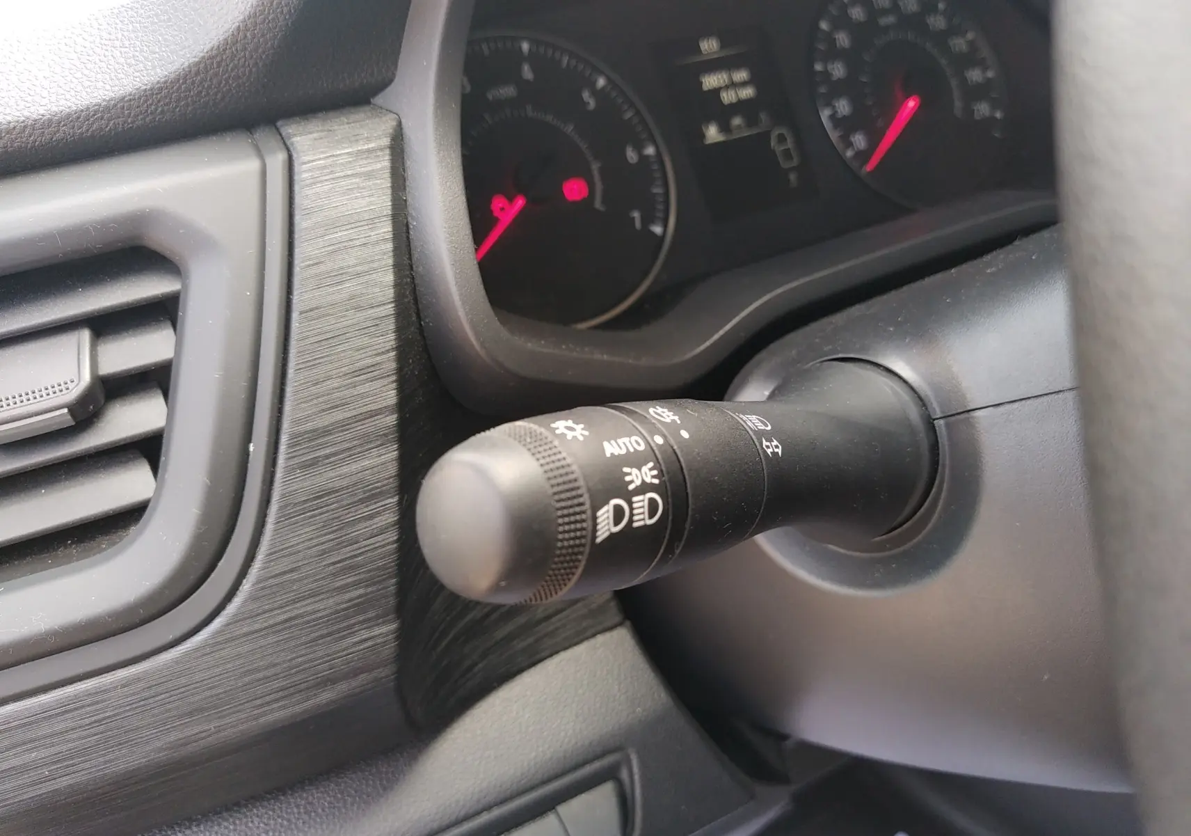 Gros plan sur la commande des feux et clignotants à gauche du volant dans l'habitacle du Renault Trafic blanc 2024.