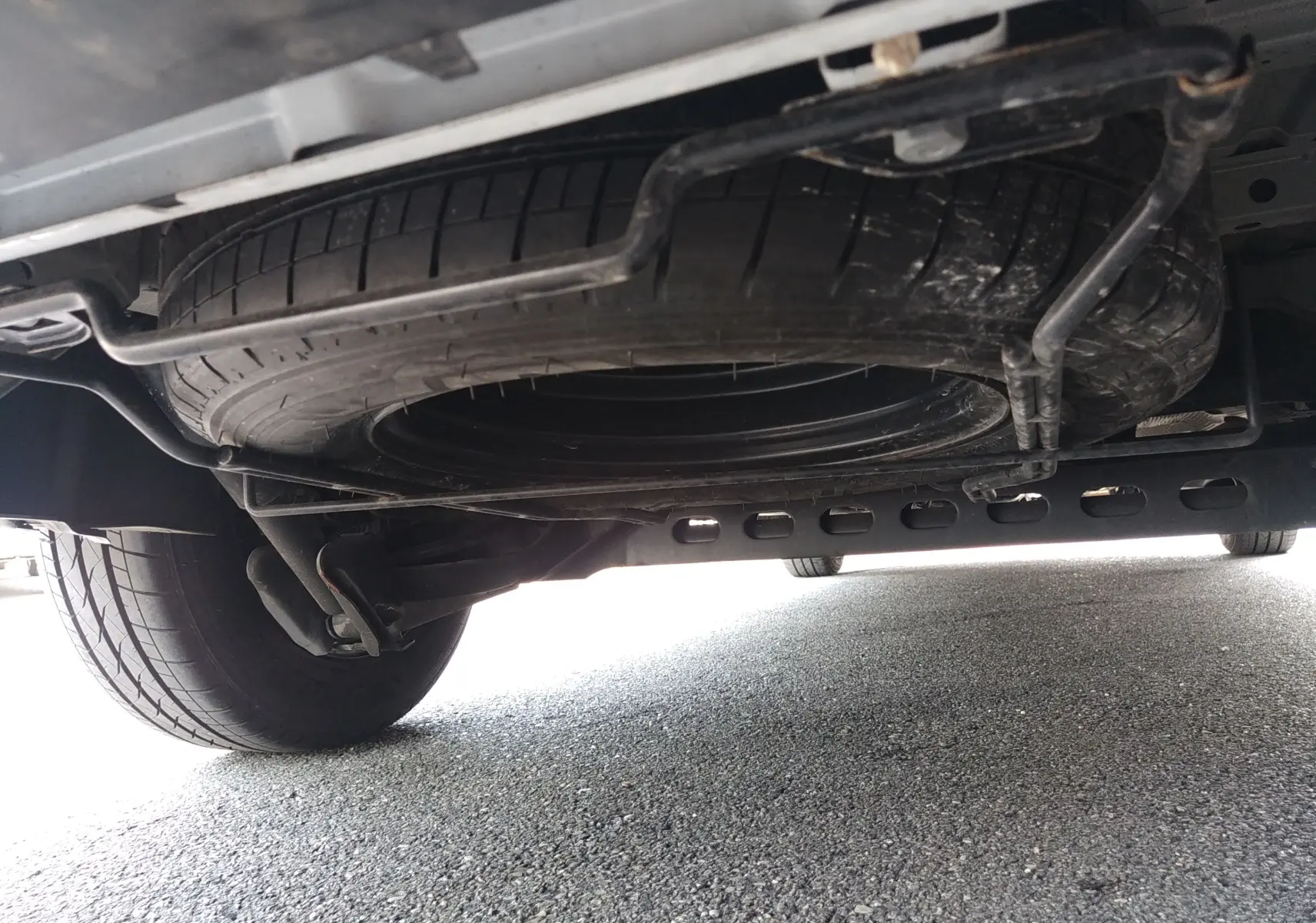 Vue en contre-plongée sous un Renault Trafic Fourgon blanc, montrant la roue de secours et le châssis arrière.
