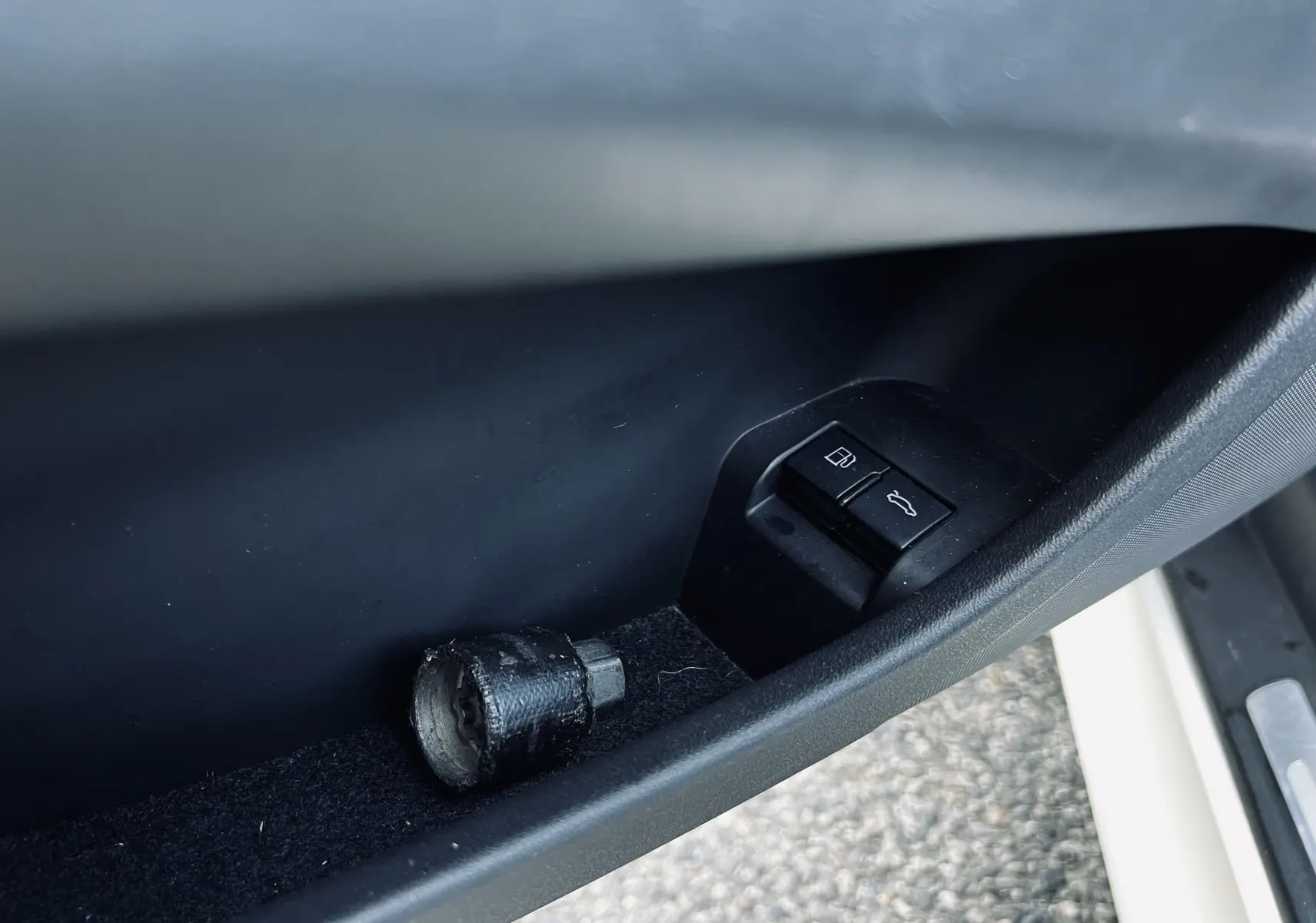 Gros plan sur la commande d'ouverture du coffre et du réservoir côté conducteur d'un Audi TT RS Roadster blanc.