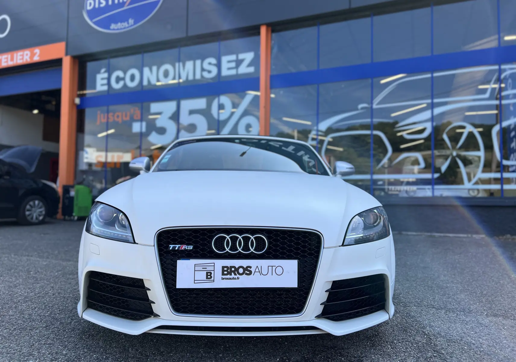 Vue frontale d'un Audi TT RS Roadster blanc avec calandre noire et logo Audi bien visible.