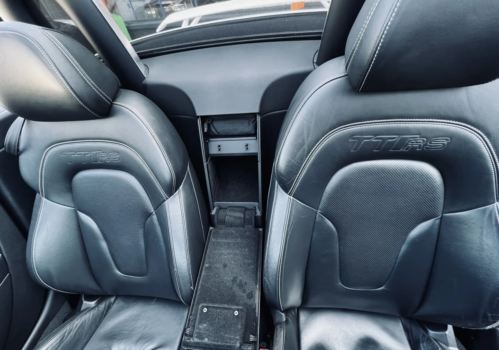 Gros plan sur les sièges baquet noirs en cuir embossés TT RS de l'Audi TT RS Roadster blanc, vue intérieure avant.