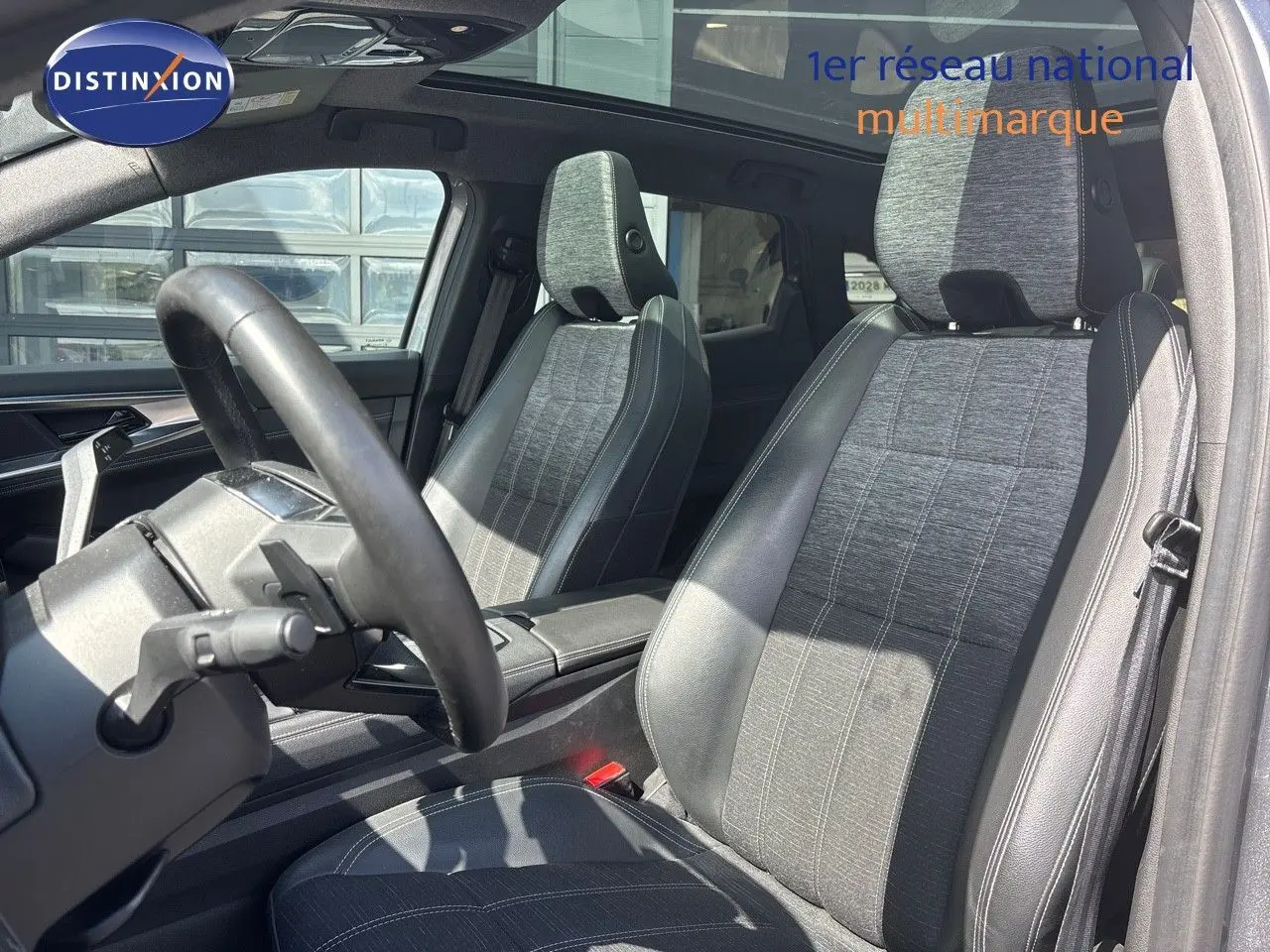 Intérieur du Renault Austral 2024 montrant les sièges avant en tissu gris et cuir noir sous lumière naturelle.