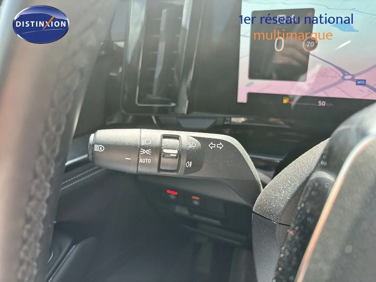 Le commodo des phares et clignotants du Renault Austral gris schiste, avec écran tactile en arrière-plan.