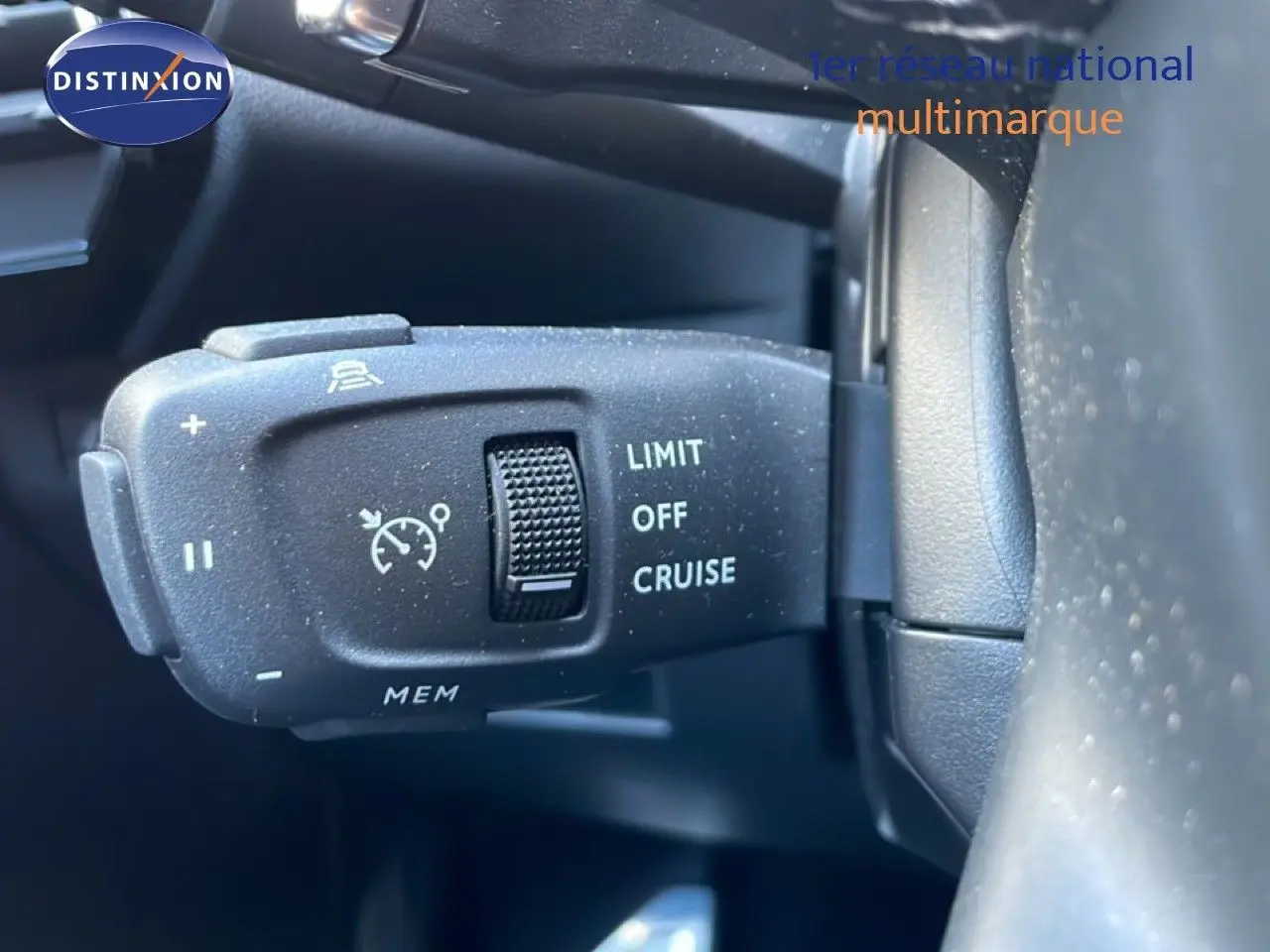 Gros plan sur la commande de régulateur de vitesse à gauche du volant dans un DS7 noir métal 2024.