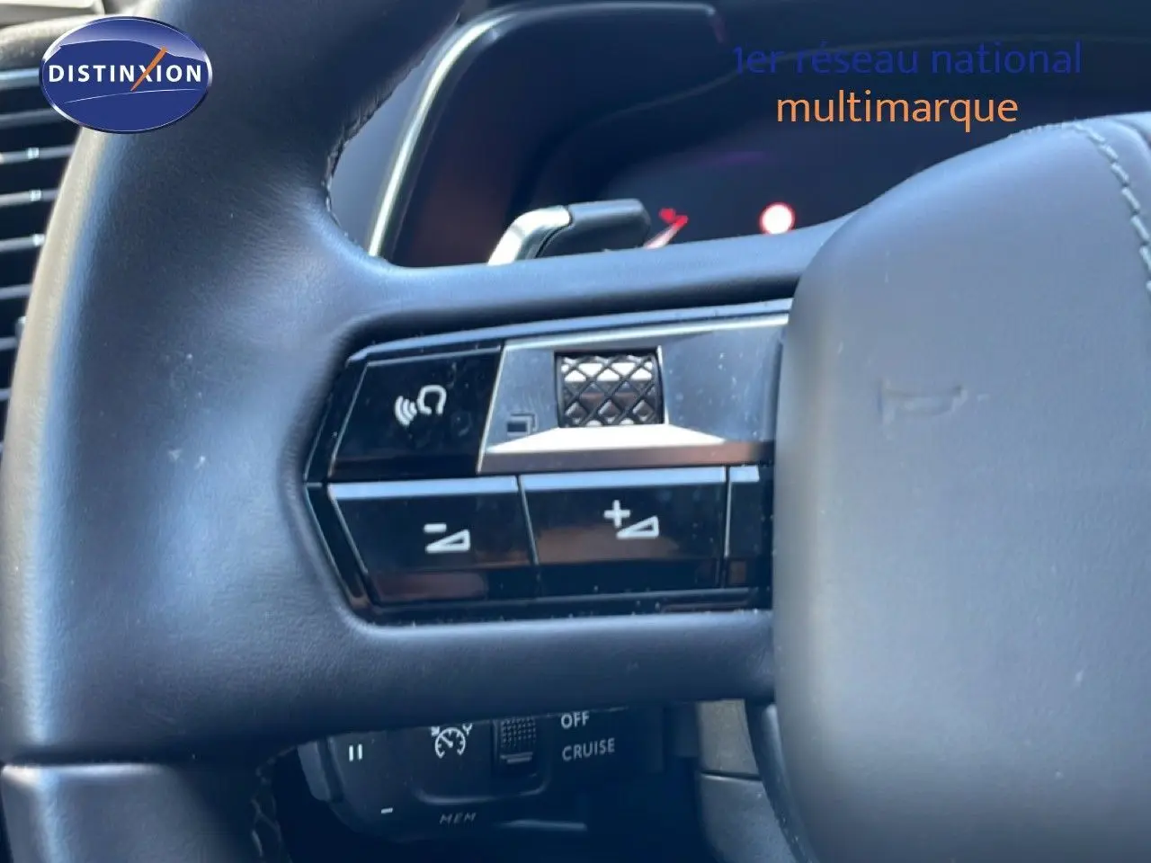 Gros plan sur les commandes gauche du volant en cuir noir du DS7 2024, avec boutons de volume et fonction mains libres.