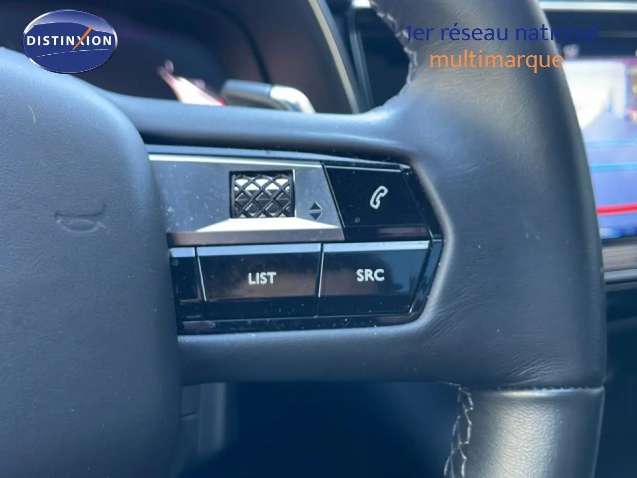 Gros plan sur les commandes gauche au volant cuir noir du DS7 2024 version BlueHDi, avec boutons LIST et SRC visibles.