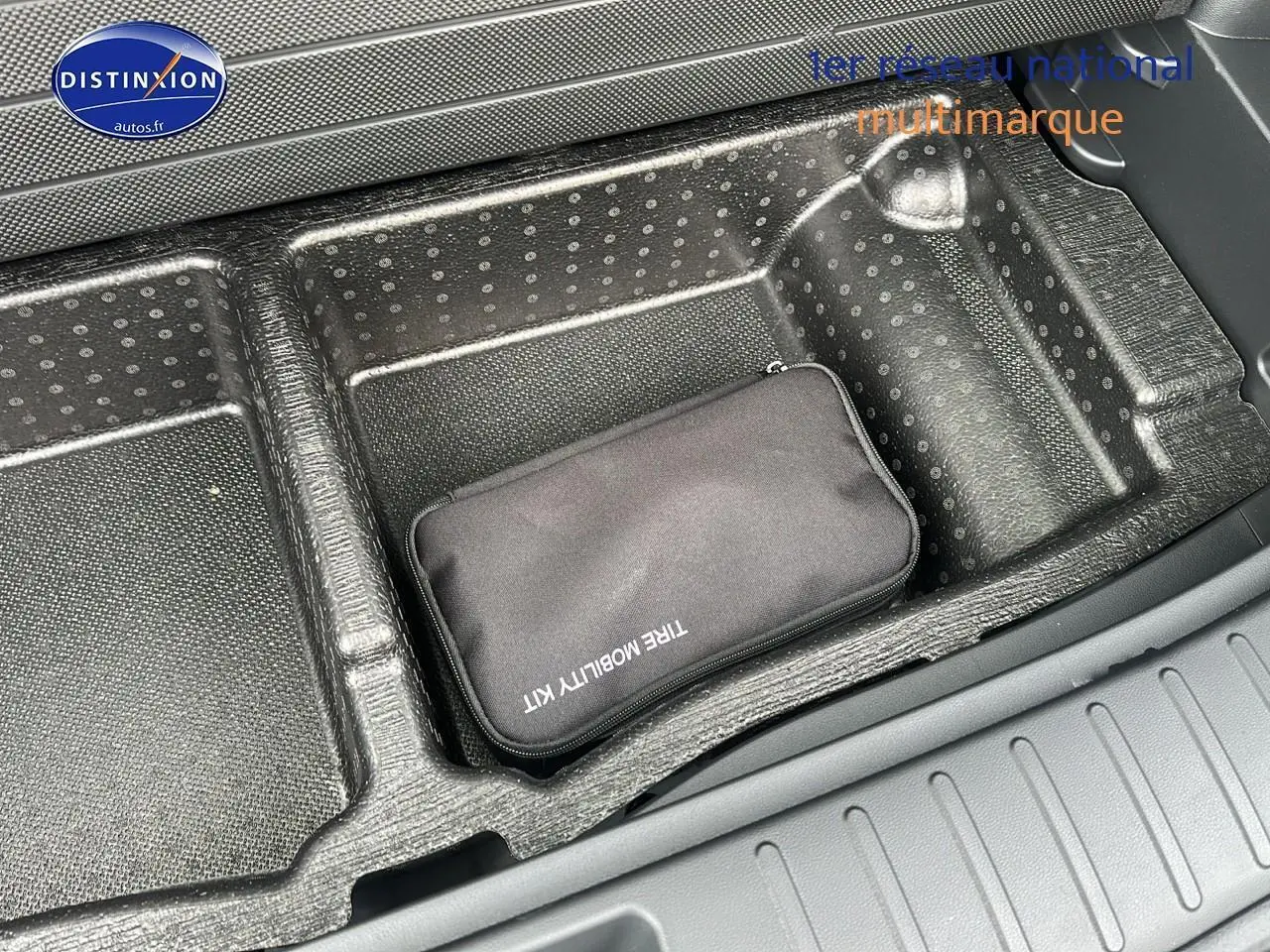 Rangement de coffre avec kit de mobilité noir dans un Hyundai Tucson blanc sérénité, vue intérieure arrière.