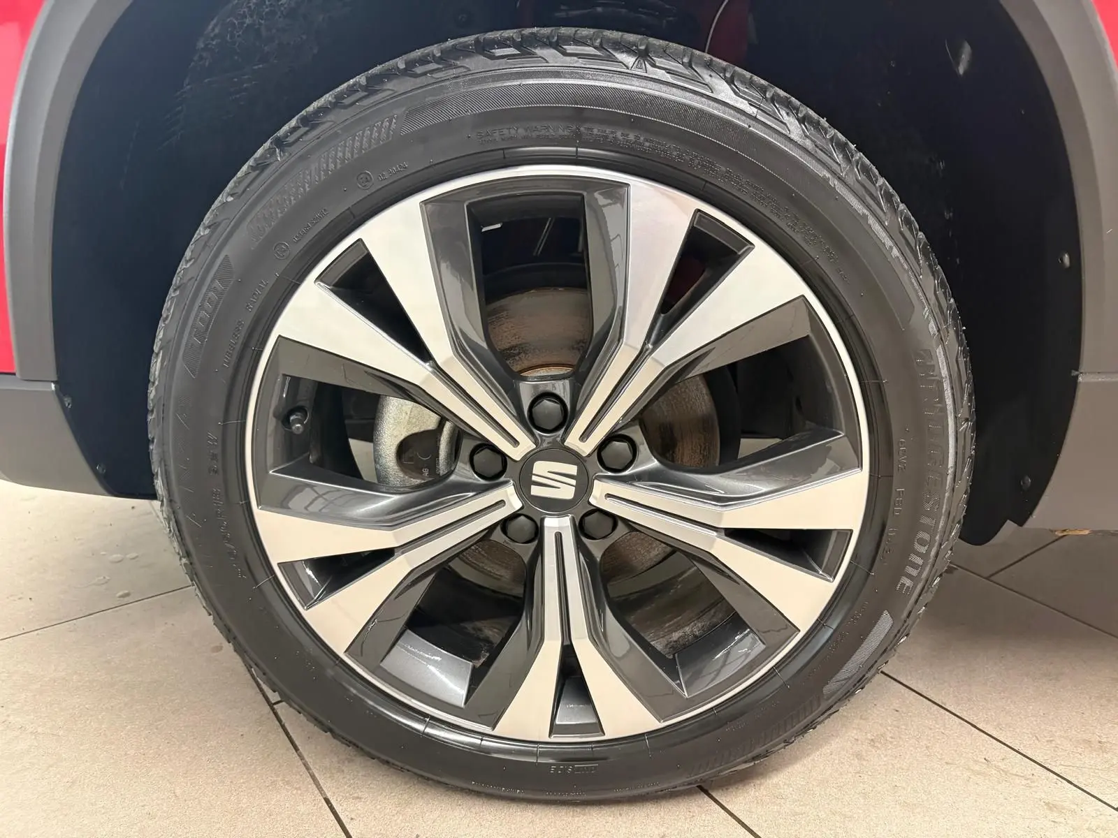 Gros plan sur la roue avant droite avec jante alliage bicolore du SEAT Ateca Rouge Velvet 2024.