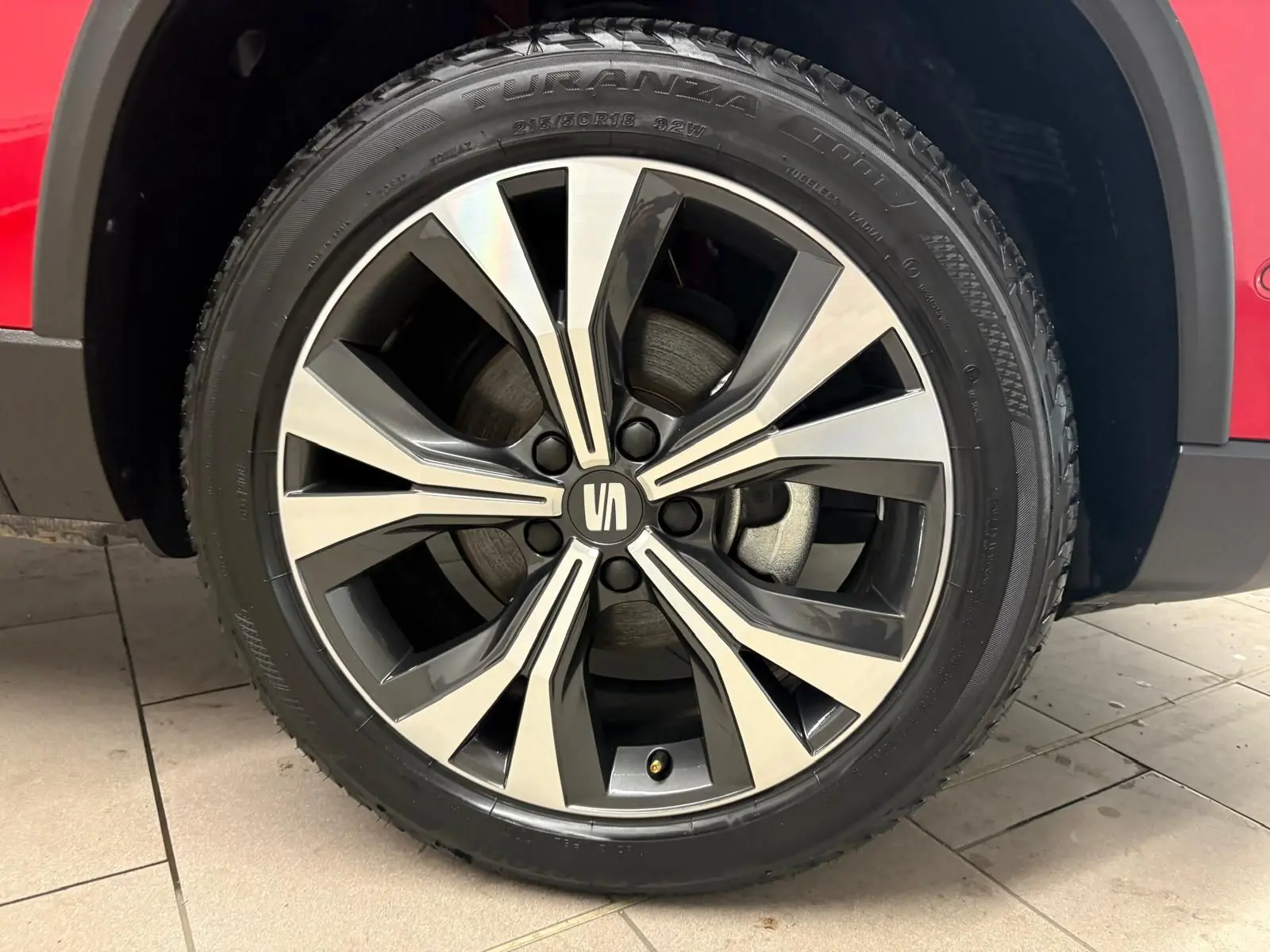 Gros plan sur la roue avant droite du SEAT Ateca 2024 Rouge Velvet, mettant en valeur la jante alliage bicolore.