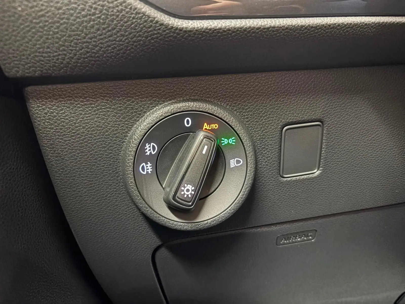 Détail du bouton de commande des phares sur le tableau de bord noir d’un SEAT Ateca 2024.