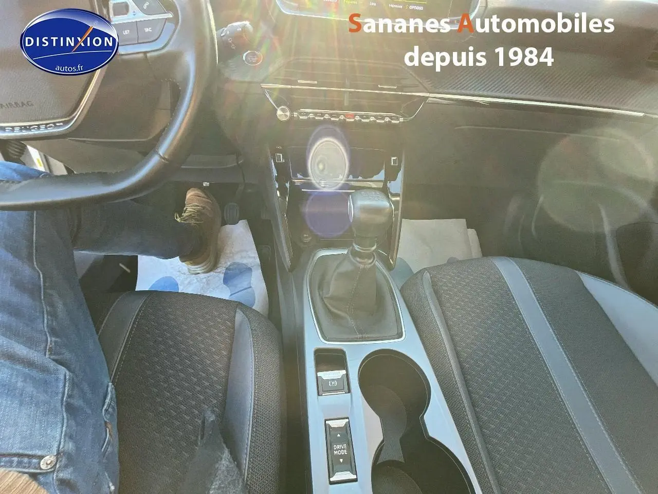 Vue intérieure centrée sur la console centrale et levier de vitesse manuelle du Peugeot 2008 blanc, sièges tissu tri-matière.