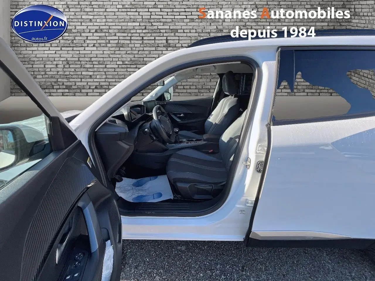 Peugeot 2008 blanc vue côté gauche avec porte avant ouverte et intérieur noir visible.