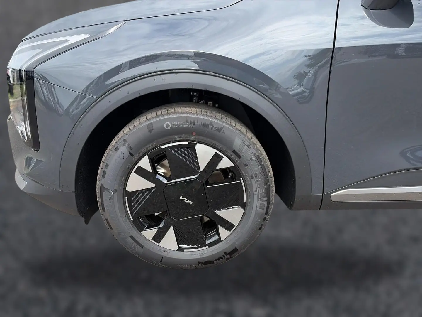 Gros plan sur la roue avant gauche d’un KIA SPORTAGE gris eclipse, mettant en valeur la jante alu 17 pouces au design moderne.