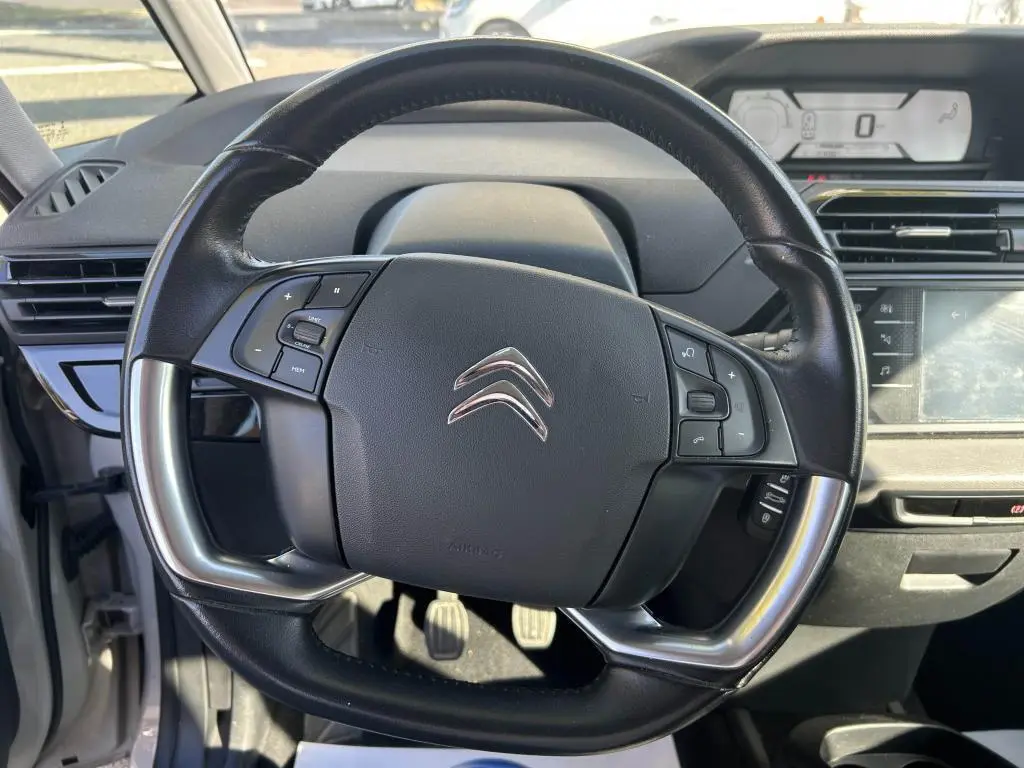 Vue rapprochée du volant multifonction noir du Citroën Grand C4 Spacetourer 2018 avec tableau de bord numérique en arrière-plan.