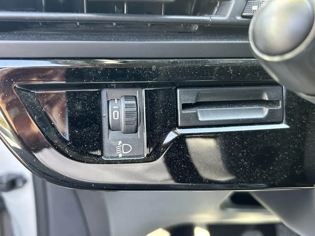 Gros plan sur le réglage de hauteur des phares dans l'habitacle noir brillant du Citroën Grand C4 Spacetourer beige clair 2018.