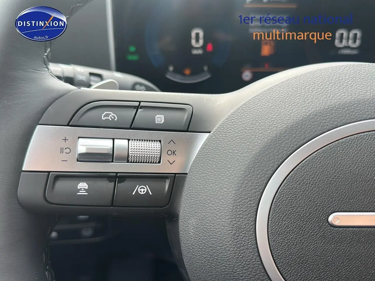 Gros plan sur les commandes multifonctions à gauche du volant cuir du Hyundai Tucson blanc Sérénité 2025 hybride.