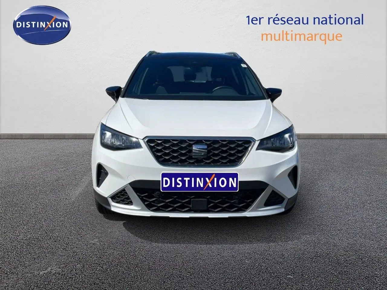 Vue frontale d'un SEAT Arona 2025 blanc à toit noir, avec calandre noire et phares LED allumés.