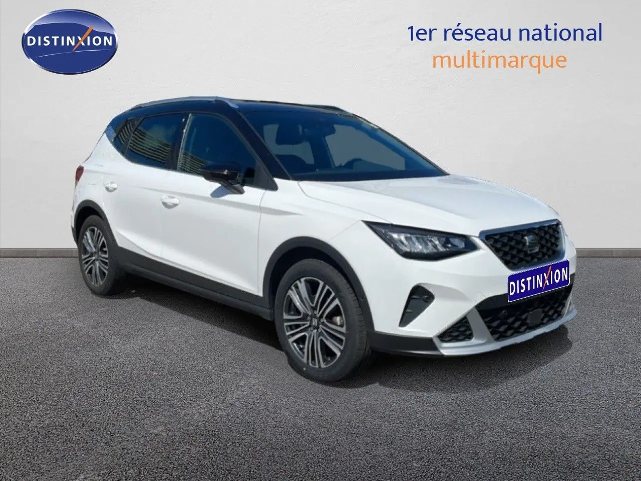 Vue 3/4 avant droite d'un SEAT Arona blanc avec toit noir, jantes alliage et calandre noire distinctive.