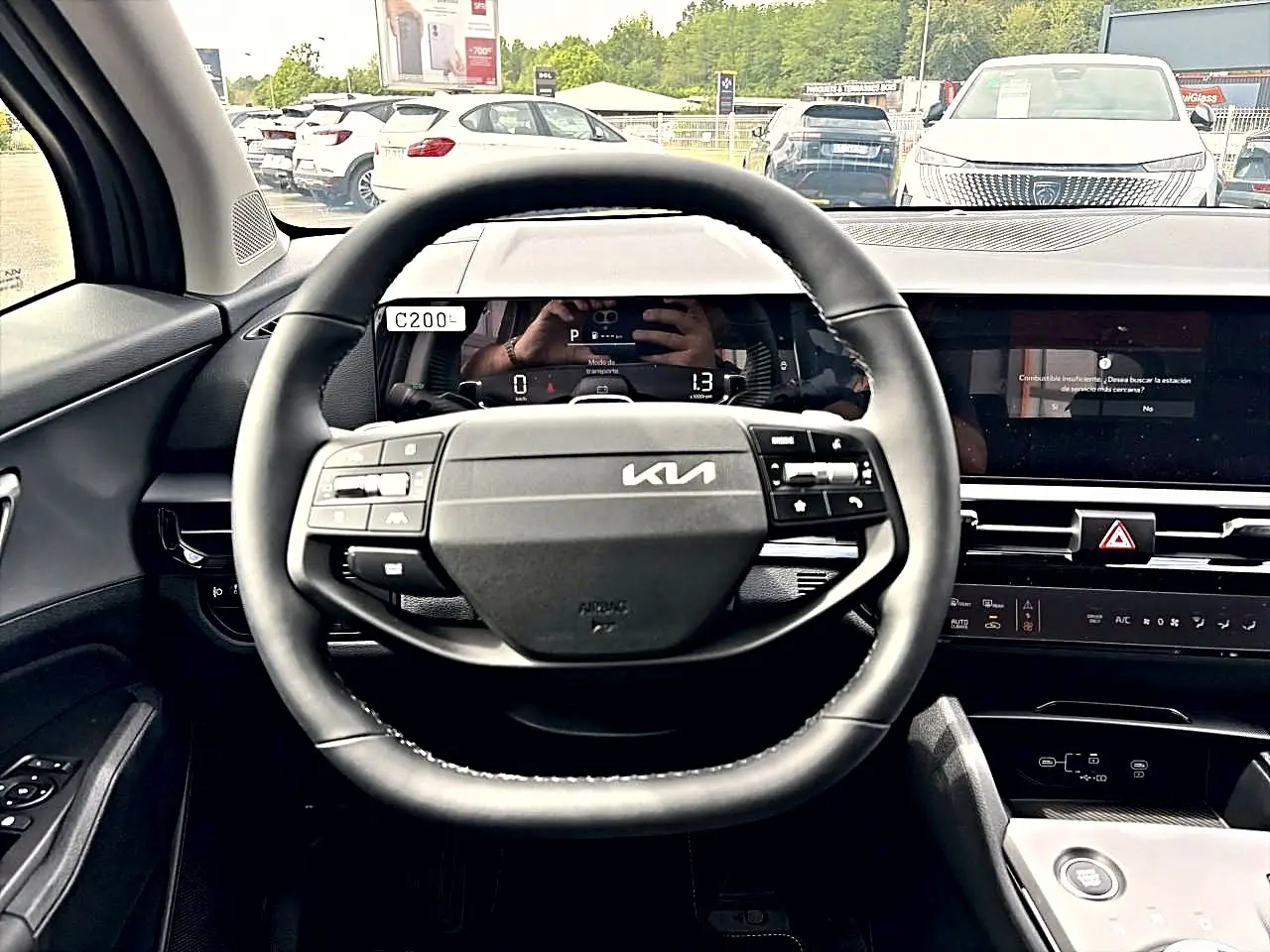 Vue intérieure centrée sur le volant noir du Kia Sportage 1.6 hybride 239 avec tableau de bord numérique et écran tactile.