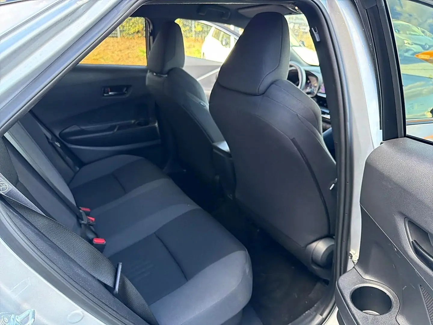Vue intérieure côté gauche sur la banquette arrière grise du Toyota C-HR 1.8 hybride 2025 avec portière ouverte.