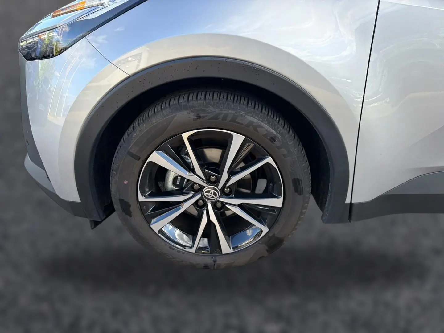 Gros plan sur la roue avant gauche du Toyota C-HR gris 2025 avec jante alliage noire et argentée.