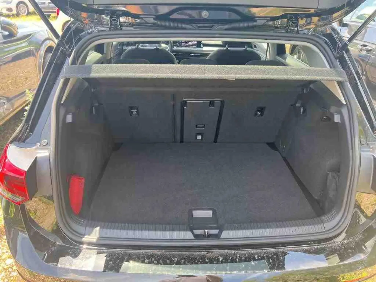 Coffre ouvert vue arrière d'une Volkswagen Golf VIII 1.5 TSI noire Deep Black, intérieur spacieux et propre.