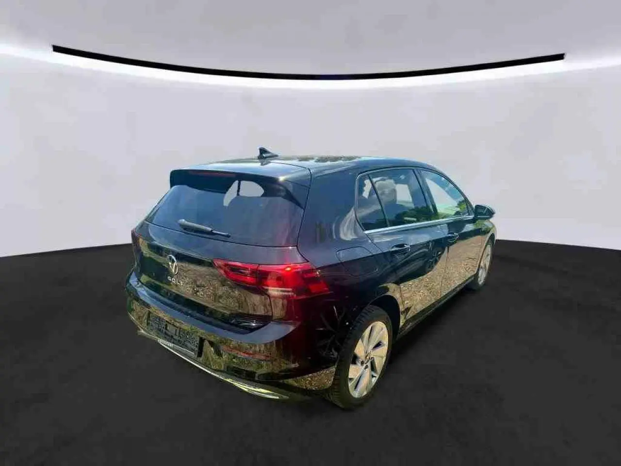 Vue 3/4 arrière droite d'une Volkswagen Golf VIII Deep Black avec vitres arrière surteintées et jantes alliage 17 pouces.