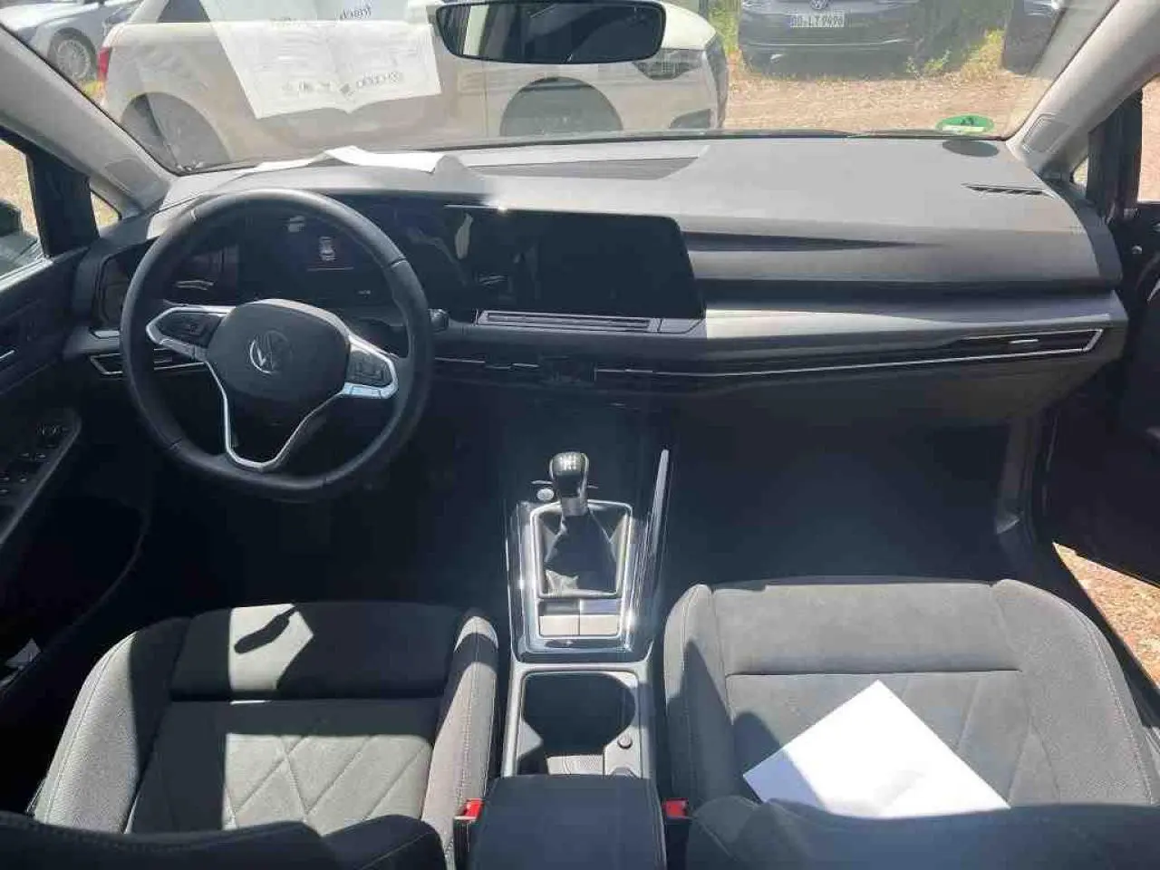 Vue intérieure avant de la Volkswagen Golf VIII 1.5 TSI noire, avec volant multifonction et boîte manuelle visible.