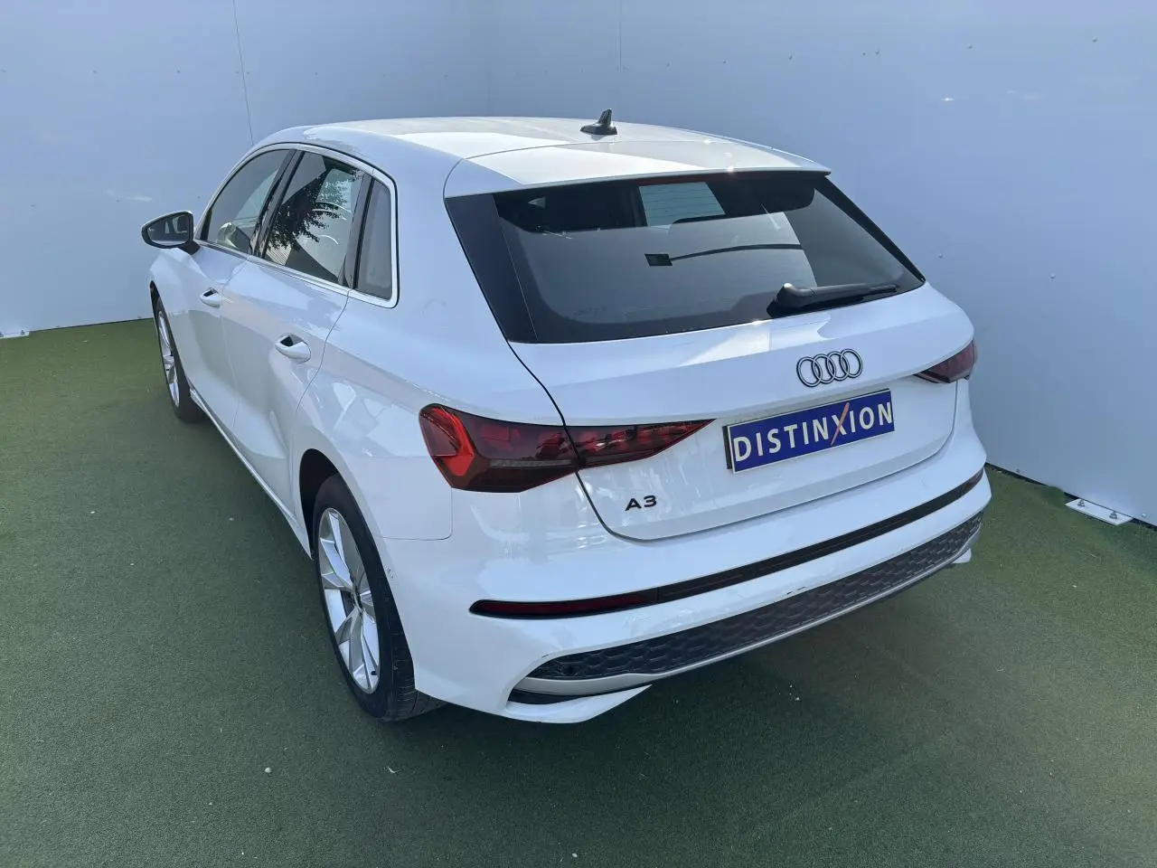 Audi A3 Sportback blanc Arkona vue 3/4 arrière droit, avec feux arrière LED et jantes alliage 5 branches parallèles.