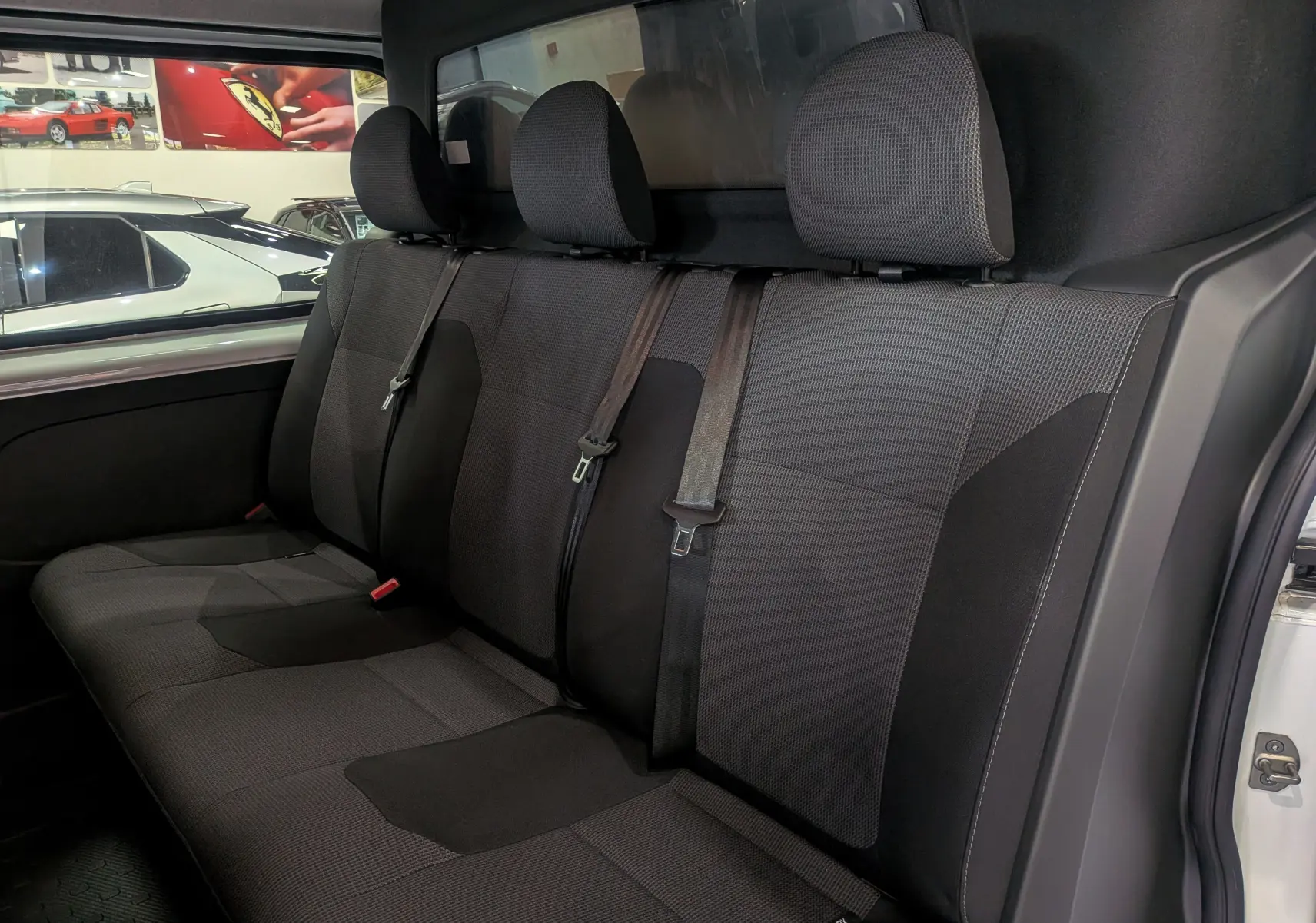 Vue intérieure côté droit des sièges arrière en tissu gris foncé du Renault Trafic Cabine Approfondie blanc minéral 2023.