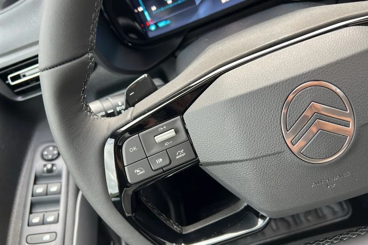 Gros plan sur le volant cuir multifonctions de la Citroën Berlingo 2026, avec commandes intégrées et tableau de bord partiel.