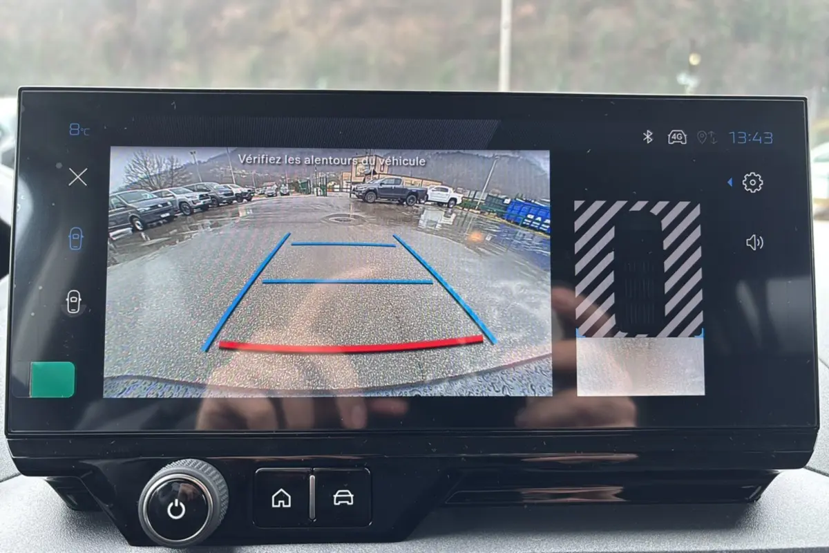 Écran tactile affichant la caméra de recul du Peugeot Rifter gris Artense, vue arrière avec lignes de guidage colorées.