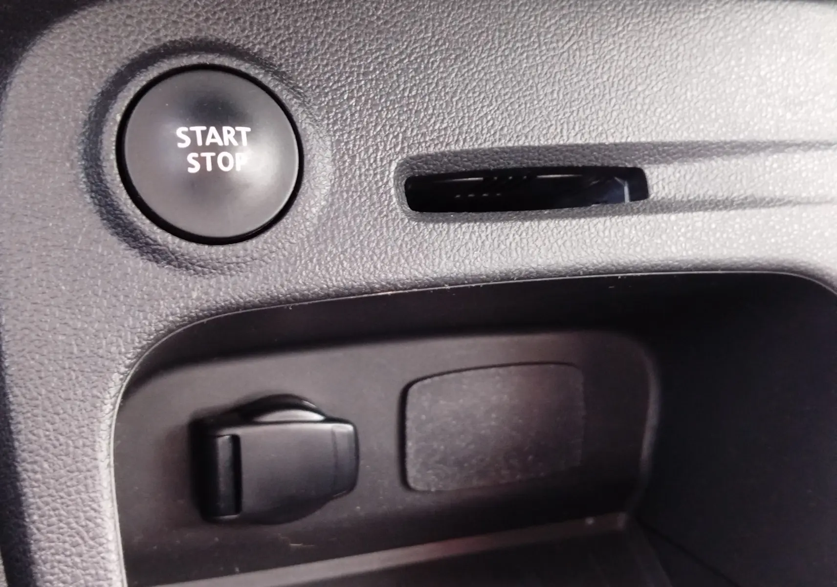 Détail intérieur du bouton Start/Stop et prise accessoires dans une Renault Captur gris Cassiopée de 2018.