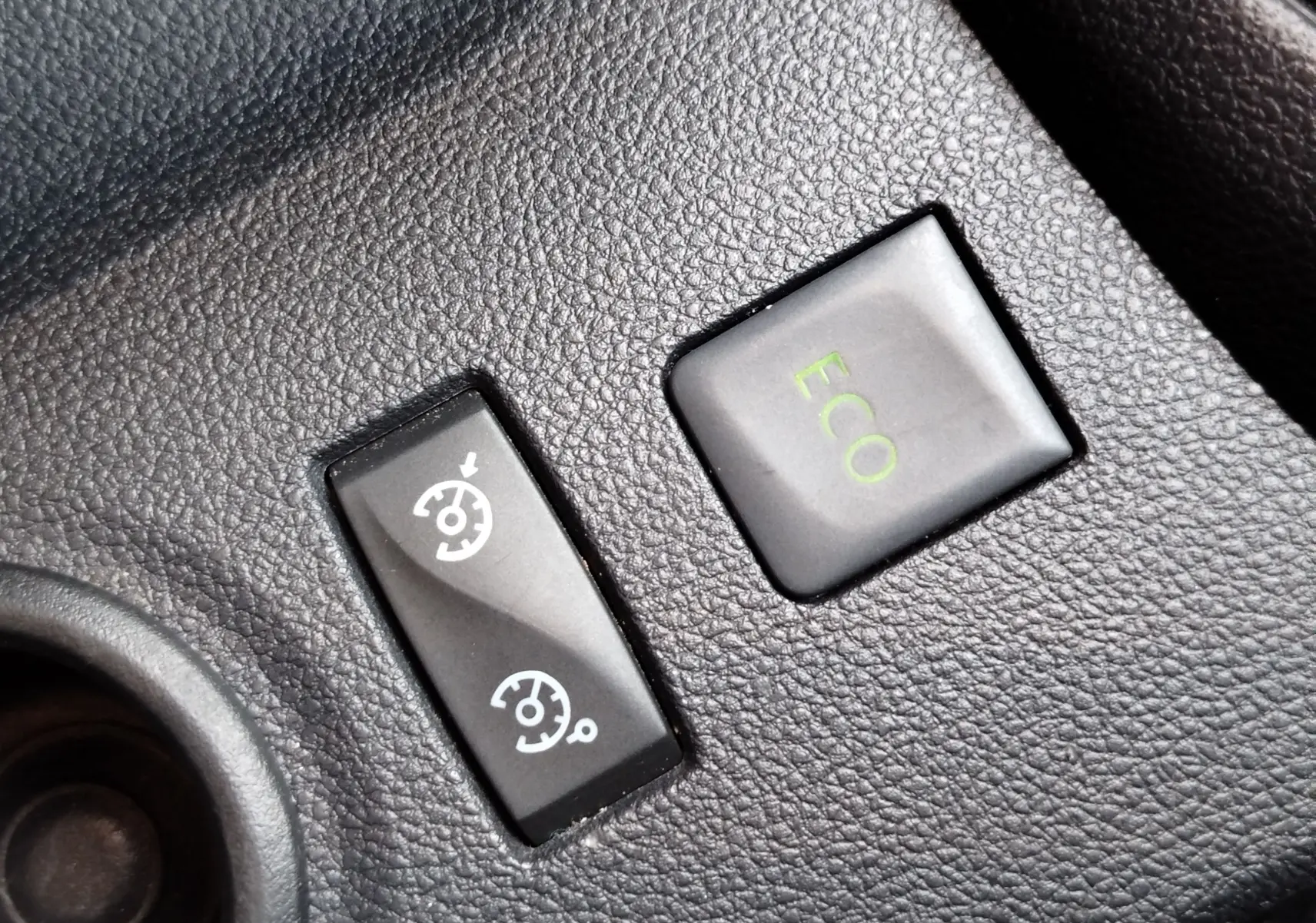 Gros plan sur les boutons de commande du régulateur de vitesse et mode ECO dans l'habitacle du Renault Captur gris Cassiopée.
