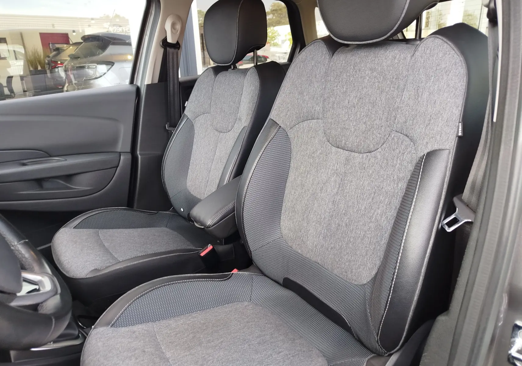 Vue intérieure côté gauche des sièges avant gris tissu et cuir du Renault Captur 1.2 TCe Intens 2018, avec accoudoir central.