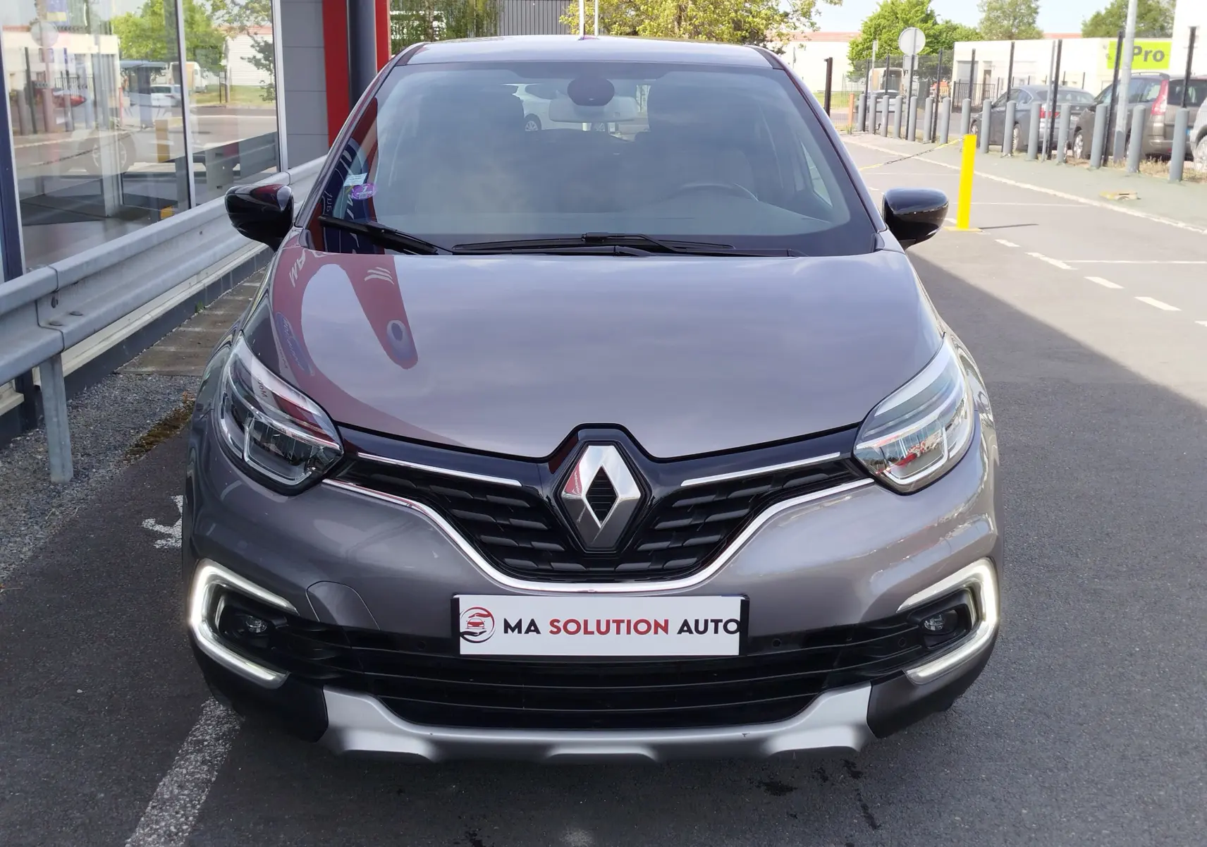 Vue frontale d'un Renault Captur gris Cassiopée 2018 avec feux diurnes LED allumés et calandre noire distinctive.