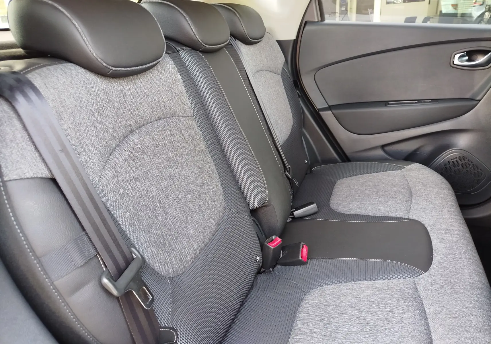 Vue latérale droite des sièges arrière gris et noirs du Renault Captur 2018, soulignant la finition tissu et cuir.