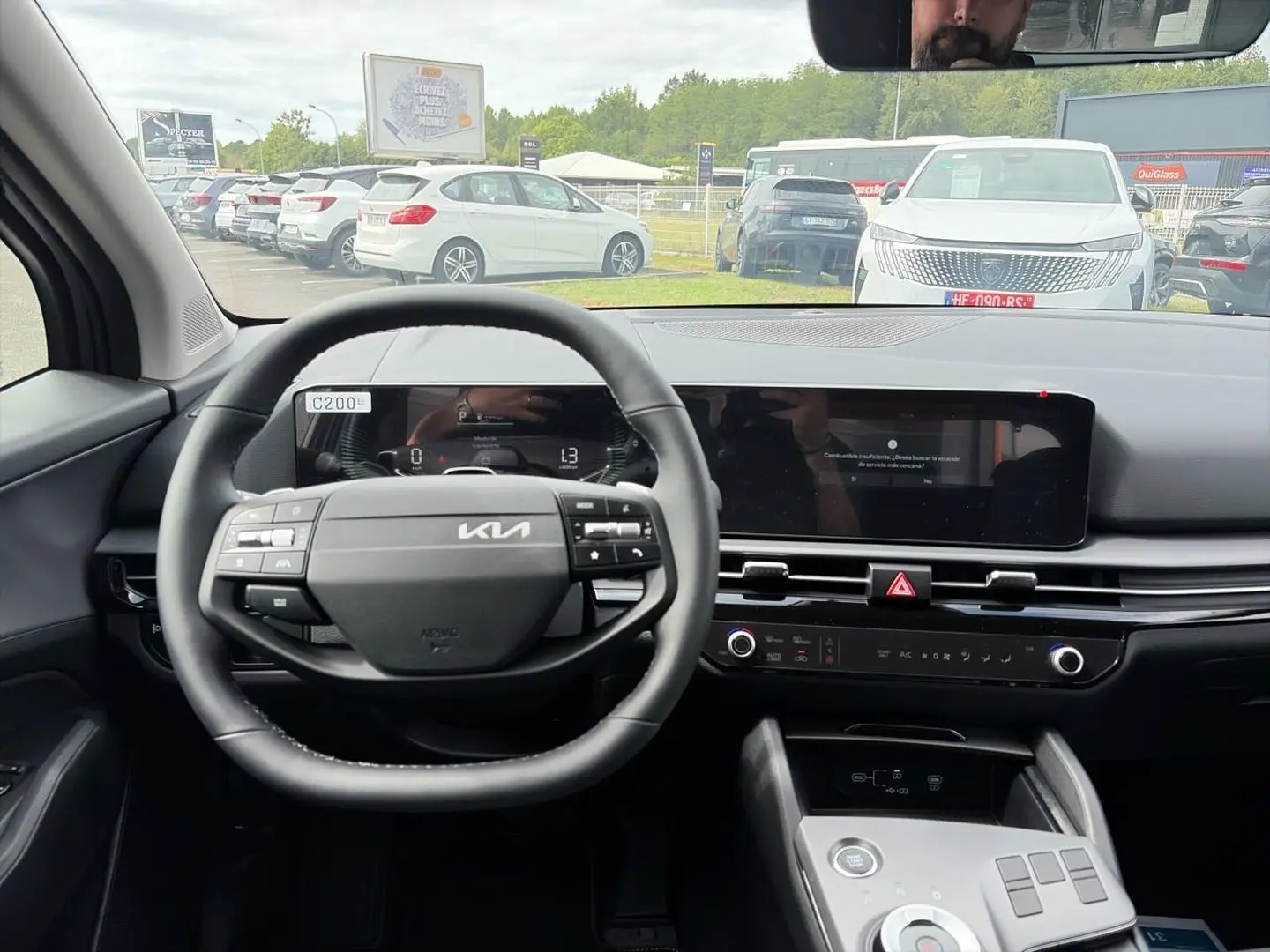 Vue intérieure centrée sur le volant cuir multifonction et tableau de bord numérique du Kia Sportage 1.6 hybride gris eclipse.