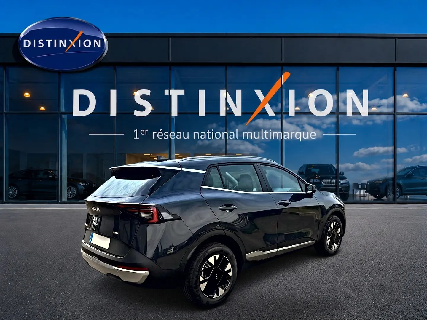 Vue 3/4 arrière droite d’un KIA SPORTAGE gris eclipse 2026 garé devant une vitrine Distinxion.