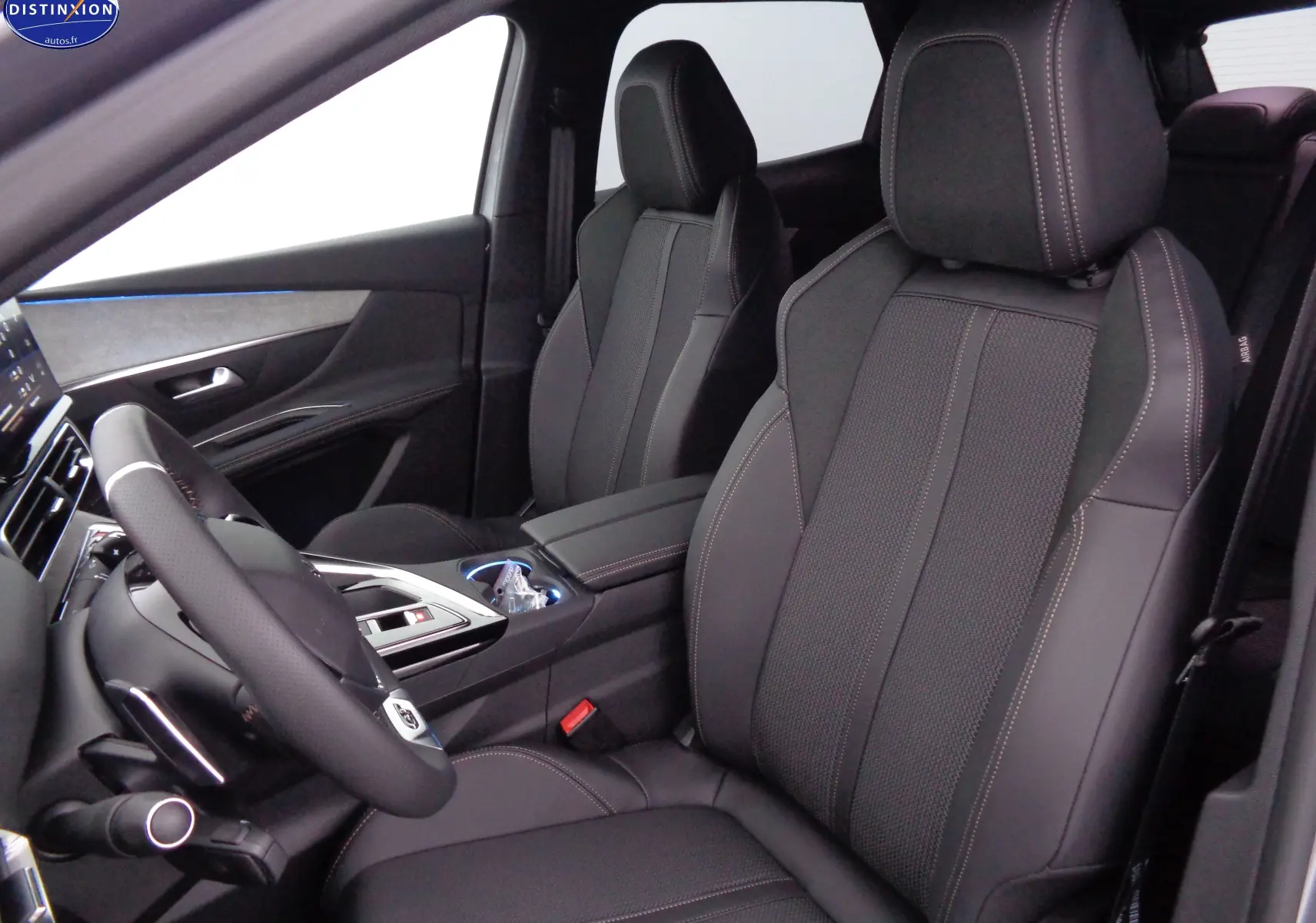 Vue intérieure côté conducteur du Peugeot 3008 2023, sièges en cuir noir avec surpiqûres contrastées et volant multifonction.