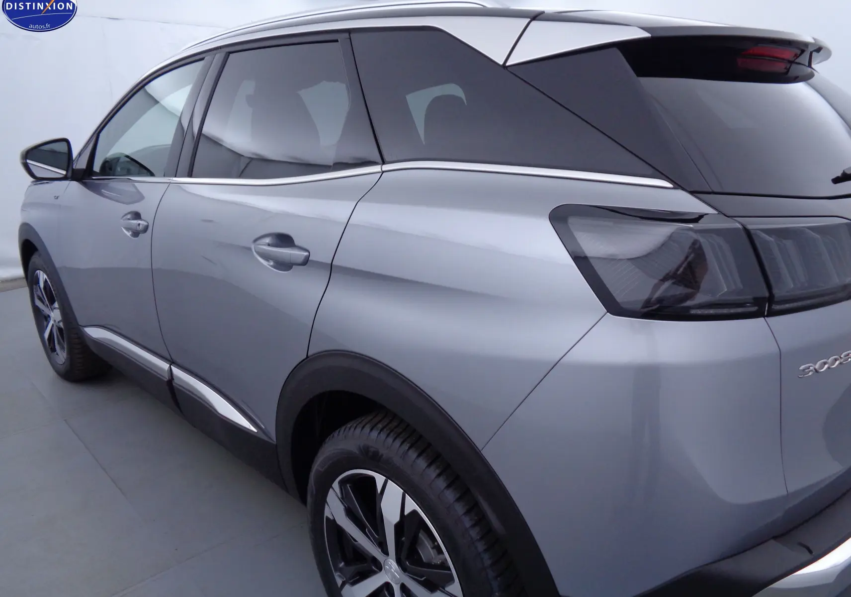 Vue 3/4 arrière droite du Peugeot 3008 gris Artense métal 2023 avec feux arrière fumés et jantes alliage bicolores.