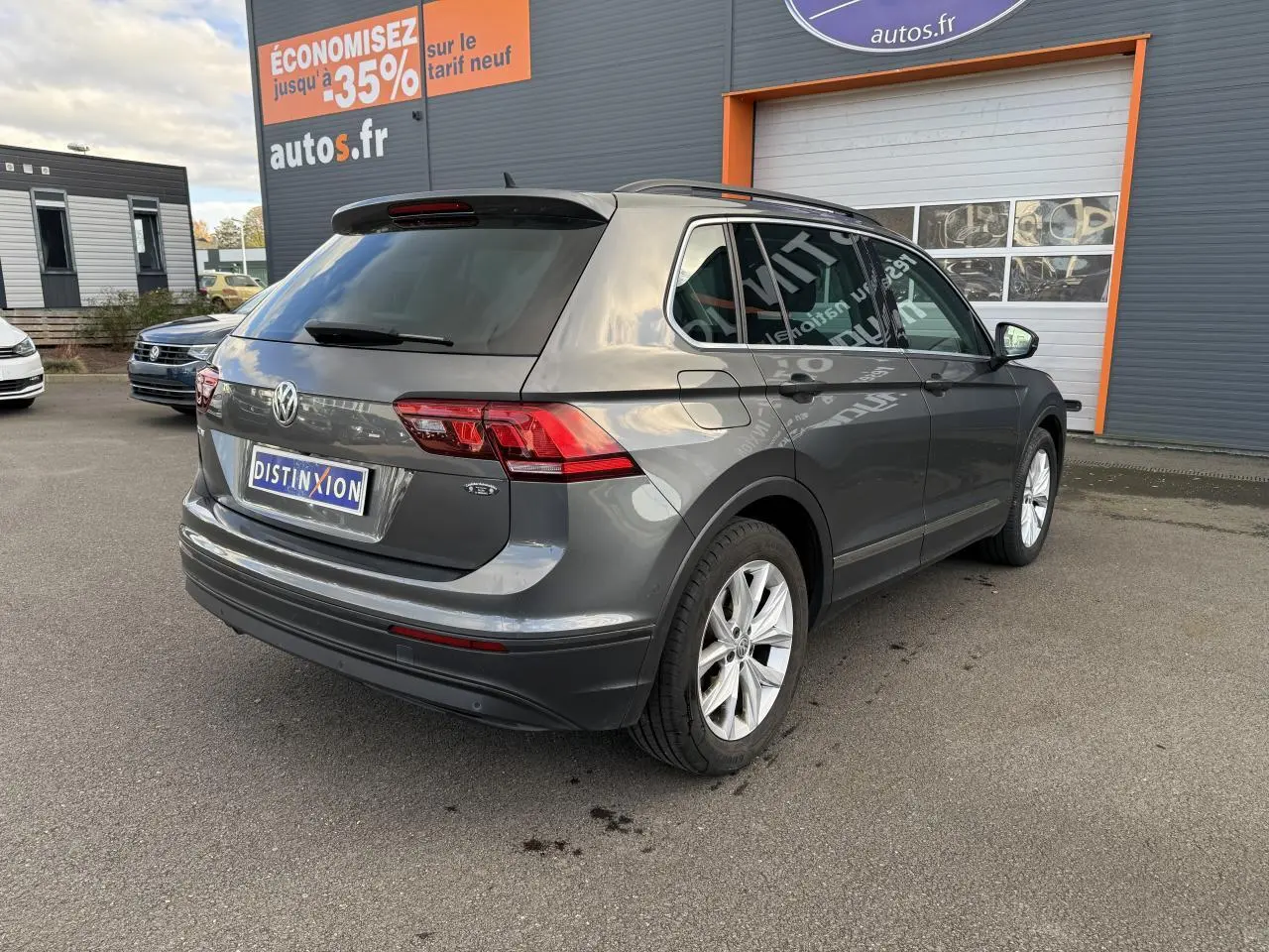 Volkswagen Tiguan gris Indium vu en 3/4 arrière droit, avec jantes alliage et vitres arrière surteintées.