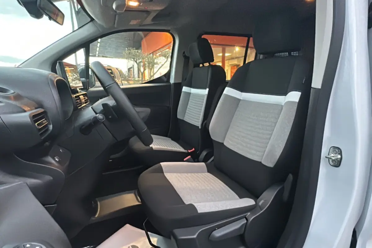 Vue intérieure côté gauche du poste de conduite du Citroën Berlingo 2026 avec sièges tissu bicolores gris et noir.