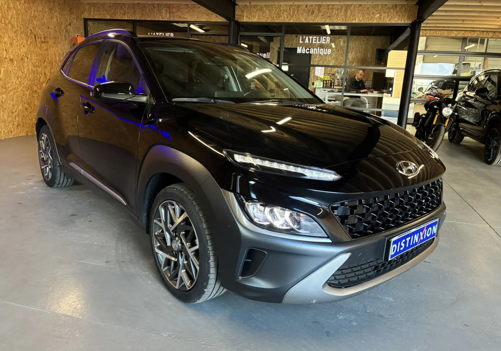 Hyundai Kona 1.6 GDI 140 Creative noir vu en 3/4 avant droit dans un garage avec éclairage intérieur.