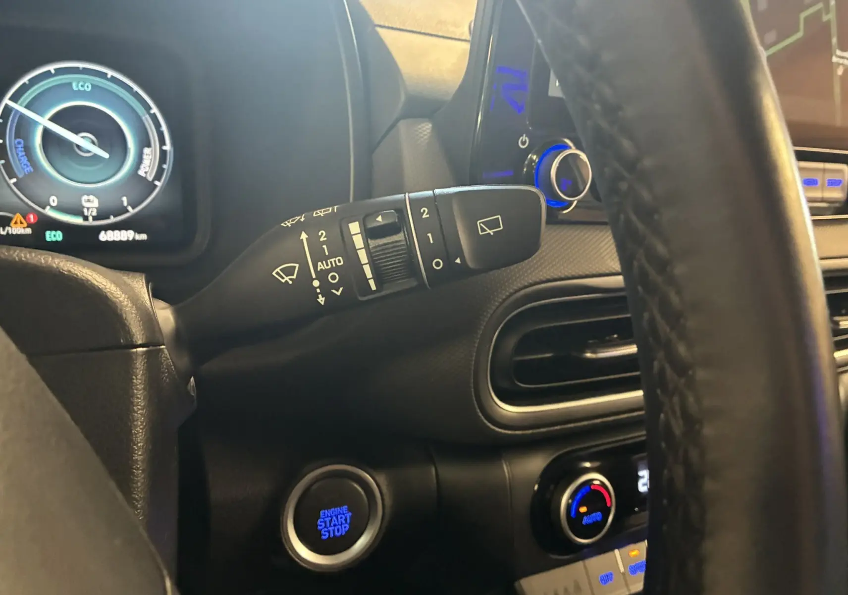 Vue intérieure du tableau de bord noir du Hyundai Kona 2023, avec volant, compteur numérique et bouton start/stop éclairé.