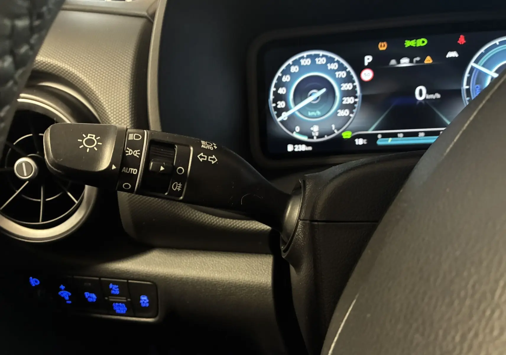 Gros plan sur le commodo des phares et le tableau de bord numérique du Hyundai Kona noir hybride 2023.