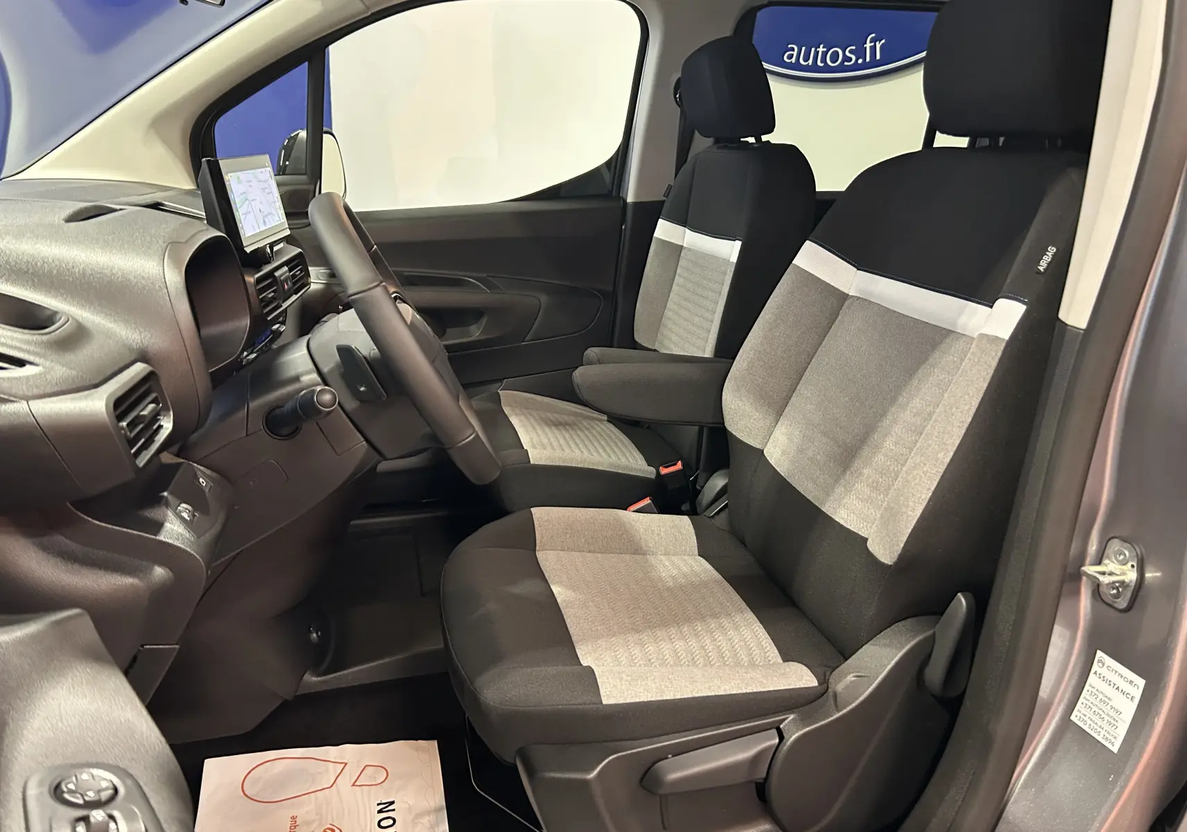 Intérieur avant du Citroën Berlingo Multispace gris, sièges tissu bicolore gris et noir, volant et tableau de bord visibles.