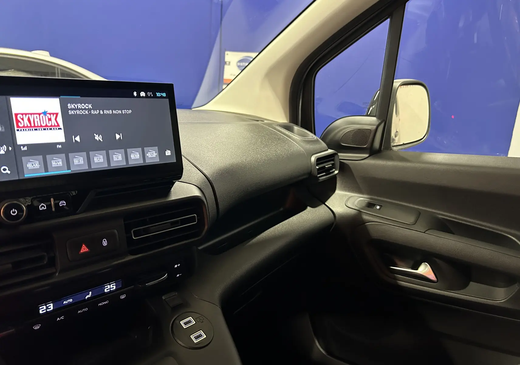 Intérieur côté passager du Citroën Berlingo Multispace 2025, tableau de bord noir avec écran tactile et commandes climatisation.