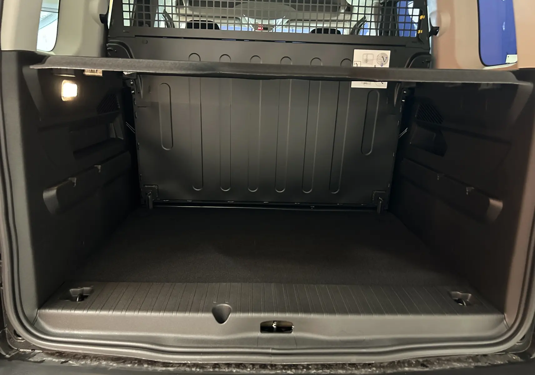 Coffre ouvert du Citroën Berlingo Multispace gris Artense, vue de l'arrière montrant l'espace de chargement et la cloison de séparation.