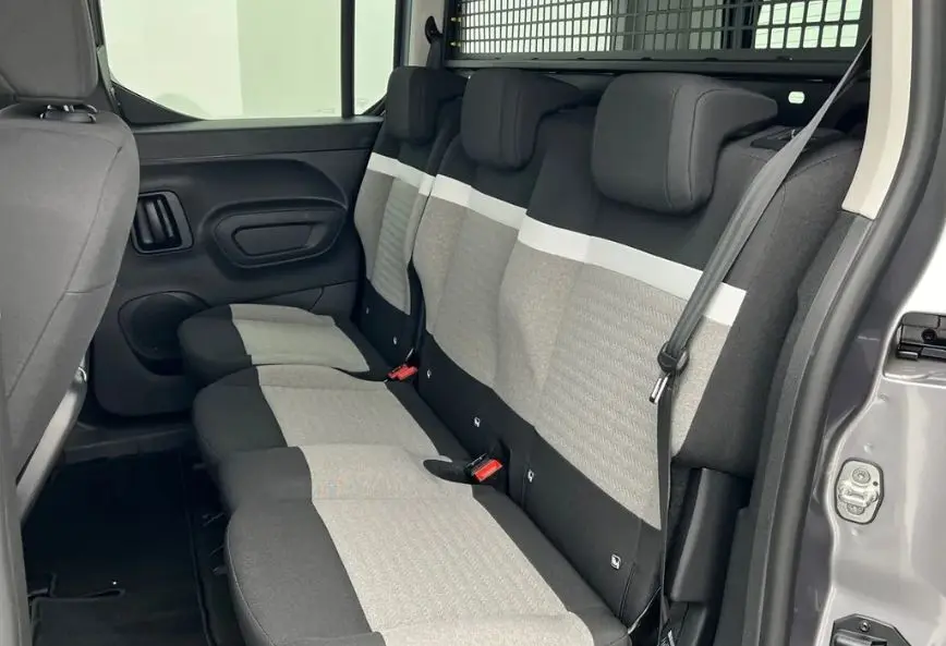 Vue latérale droite sur les sièges arrière gris clair et noir du Citroën Berlingo Multispace 2025, avec séparation grillagée.
